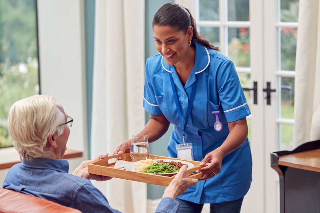 Como Prevenir Quedas de Idosos em Casa: Guia Cômodo a Cômodo 1 female care worker in uniform bringing meal on tra 2022 04 04 21 27 31 utc