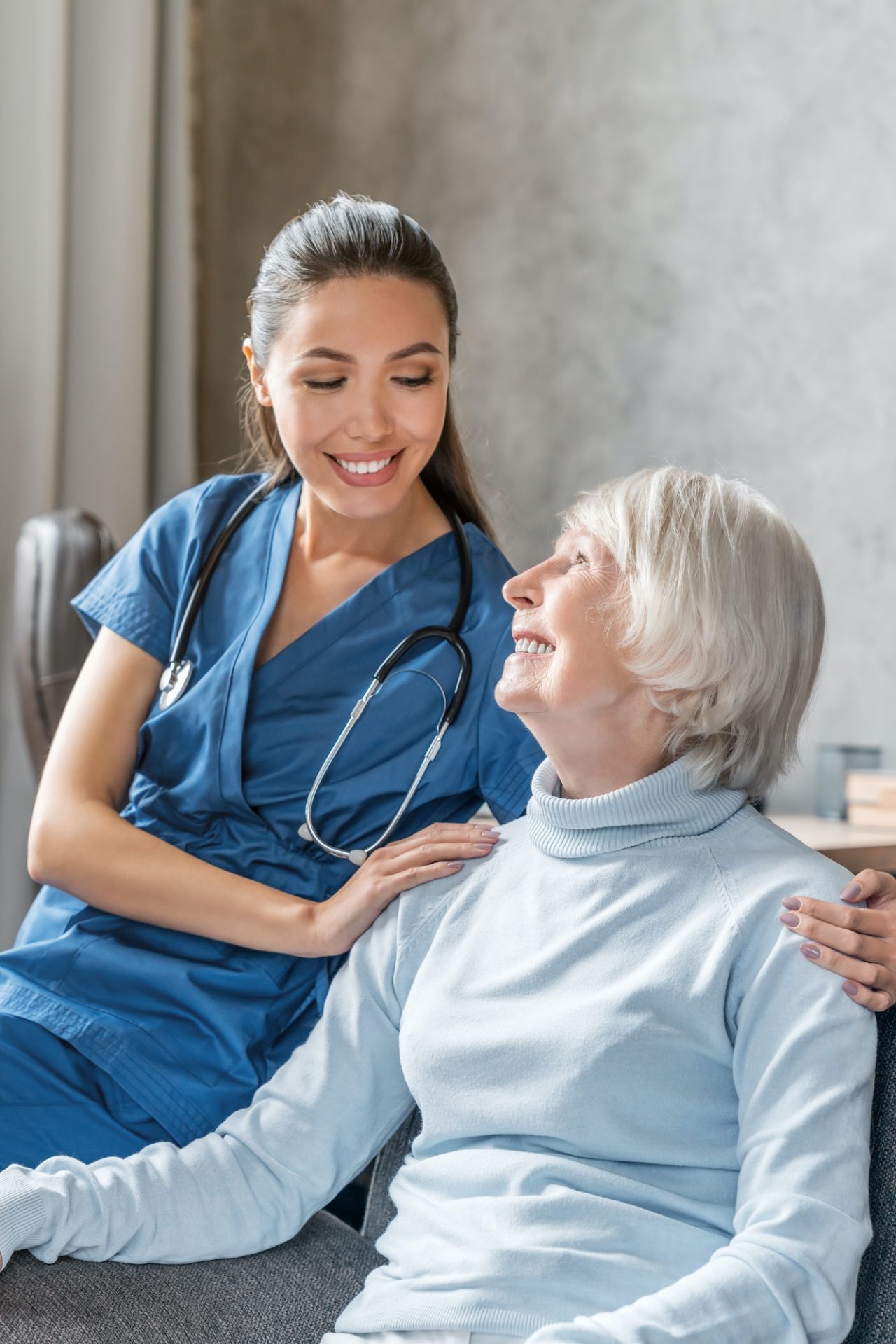 vertical portrait of happy elderly woman with nurse at home